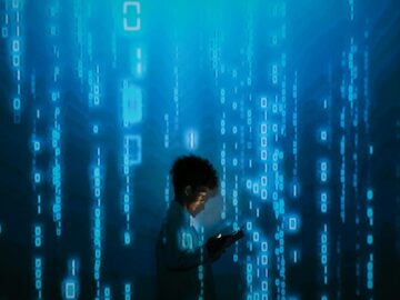 Silhouette of a person using a smartphone surrounded by digital binary code projections.
