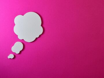 Paper thought bubble over bright pink background, ideal for creative concepts.